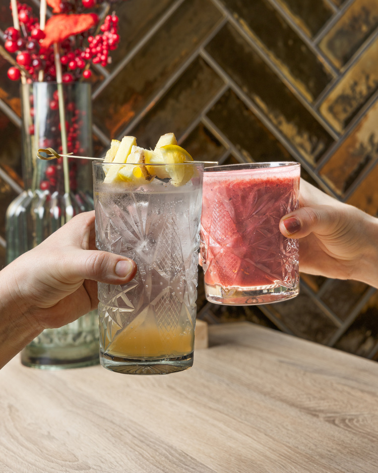 een glas met verse limonade die proost met een smoothieglas.